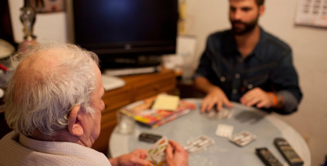 Un voluntario jugando a las cartas con una persona mayor